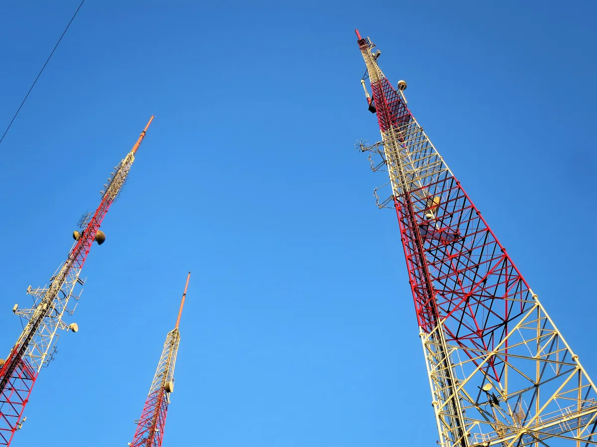 Torres de telecomunicaciones elevándose sobre un cielo azul.